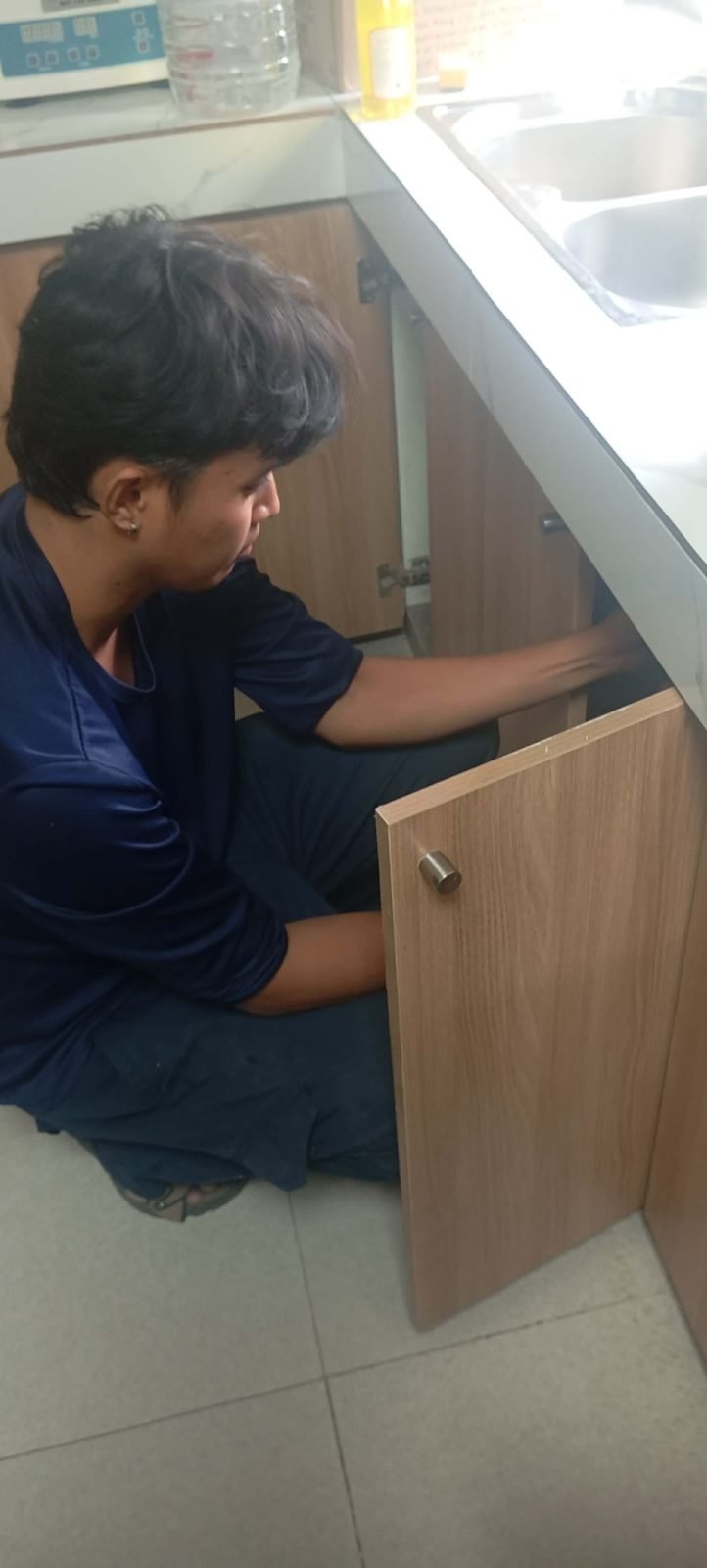 Technician inspecting under a kitchen sink cabinet