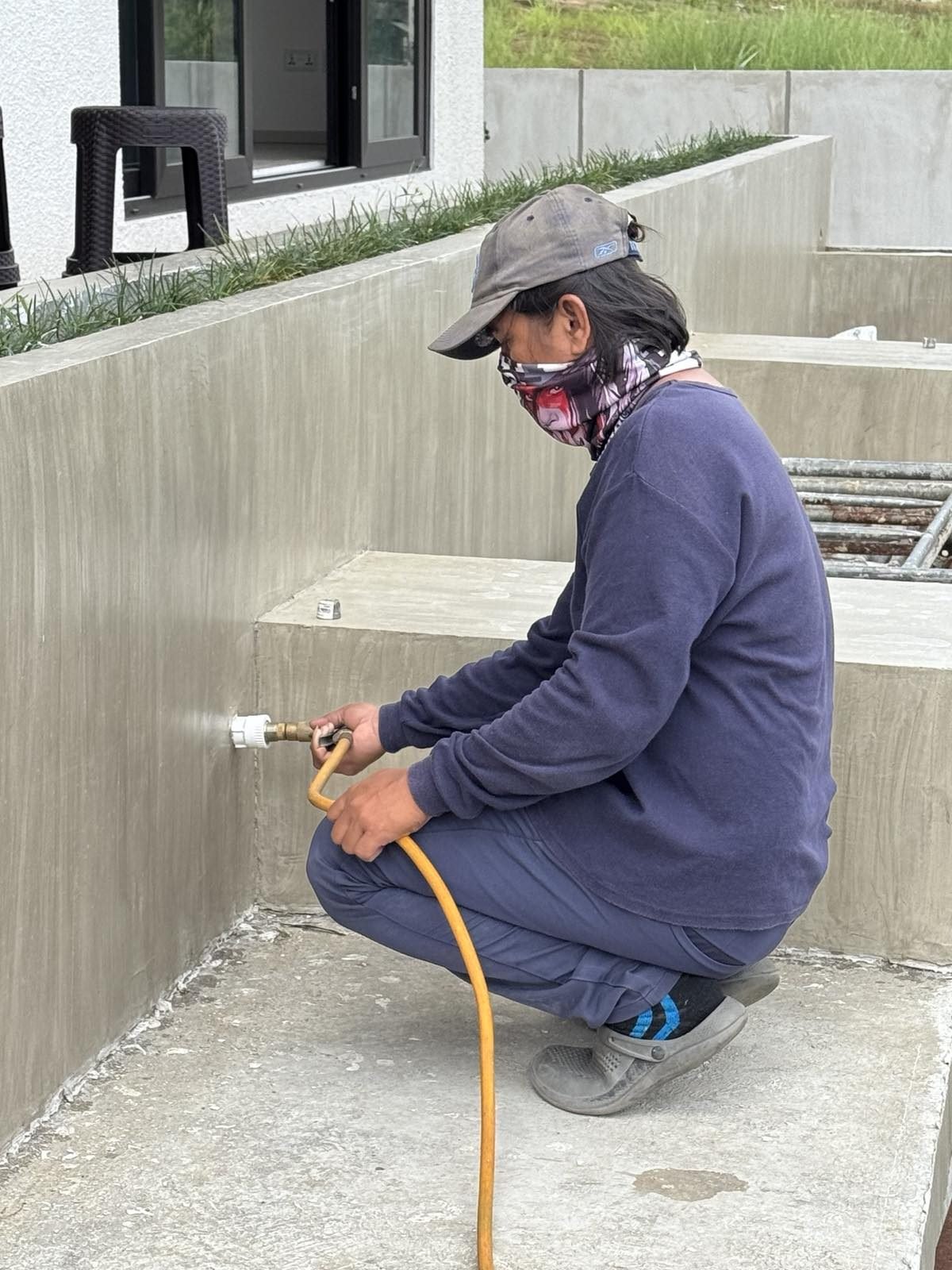 Technician injecting treatment into the base of an outdoor wall
