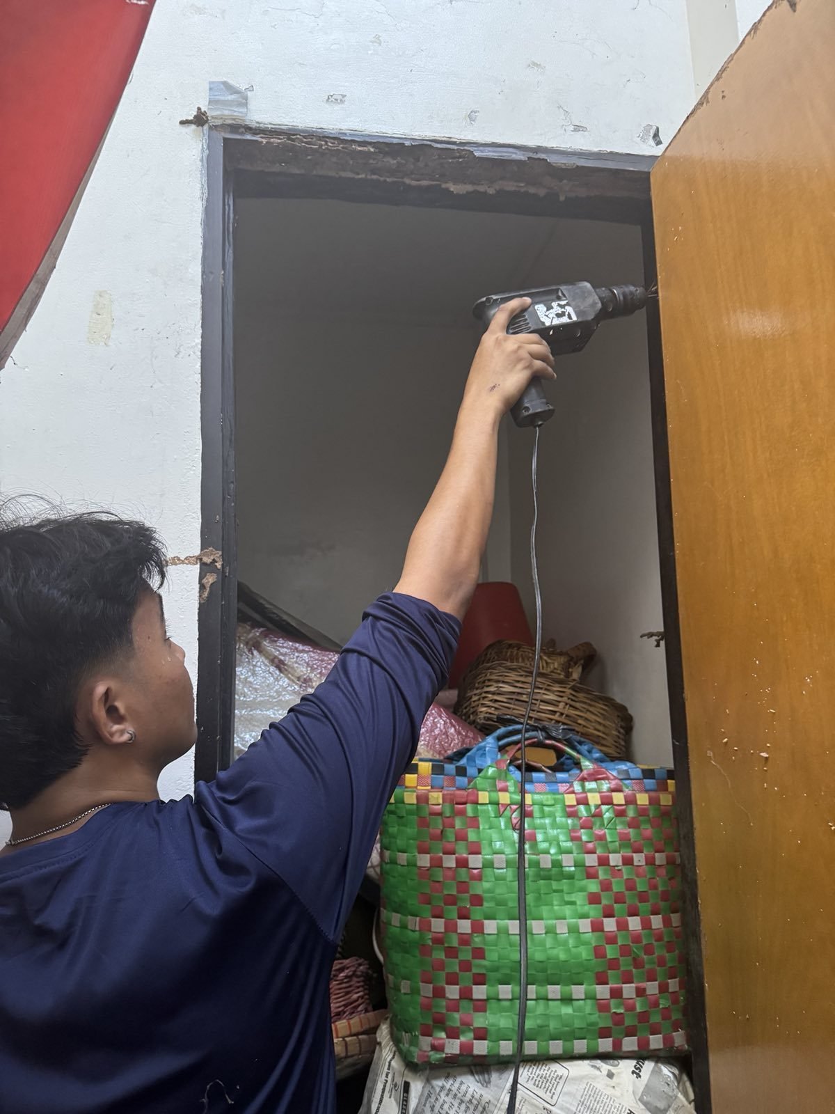 Technician drilling treatment holes in a termite-damaged door frame