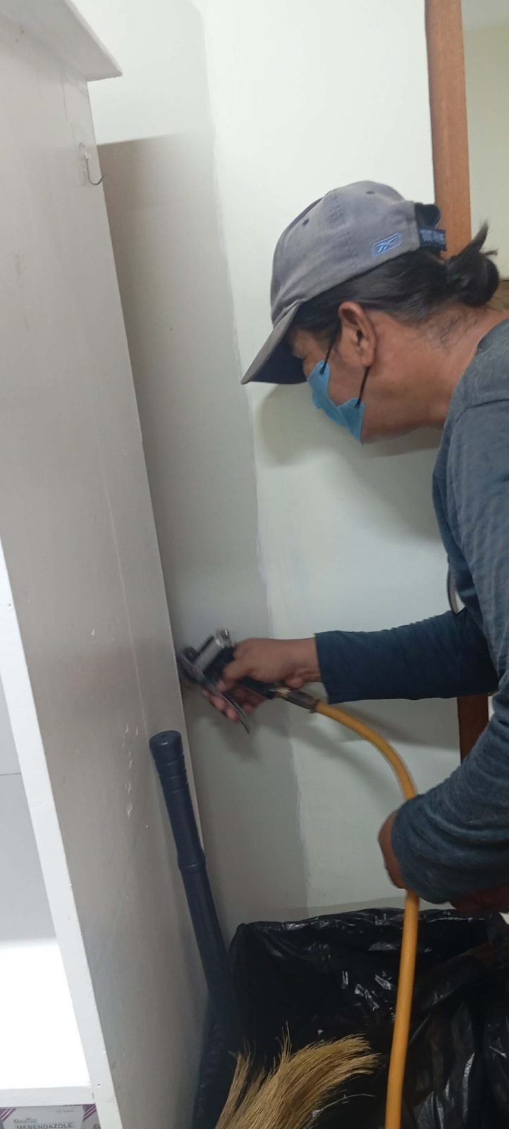 Technician injecting termiticide along the base of a wall